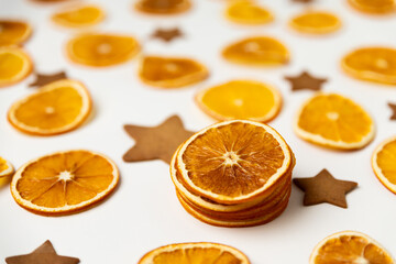 dried dehydrated orange slices, homemade handmade star shaped gingerbread cookies and red ribbon bow on white paper background. Christmas vibe texture