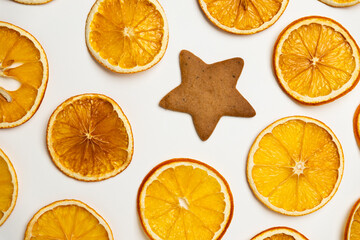 dried dehydrated orange slices, homemade handmade star shaped gingerbread cookies and red ribbon bow on white paper background. Christmas vibe texture