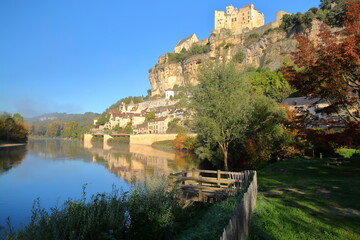 Naklejka premium The impressive village Beynac et Cazenac, Dordogne, France, blend into a magnificent cliff and overlooking the river Dordogne, with autumn morning mist and the castle on the top