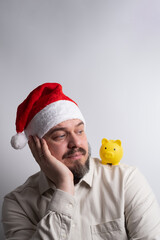Man in santa hat looking at piggy bank on shoulder
