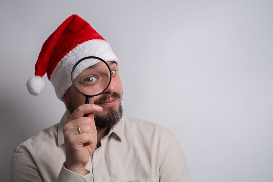 Man in santa hat looking through magnifying glass
