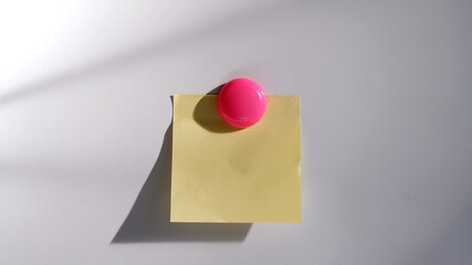 Blank yellow paper note is on the whiteboard background. Front view of one sticky note with natural...