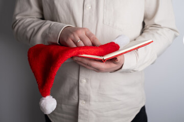 Hands holding open notebook and santa hat