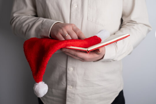Hands holding open notebook and santa hat - Powered by Adobe