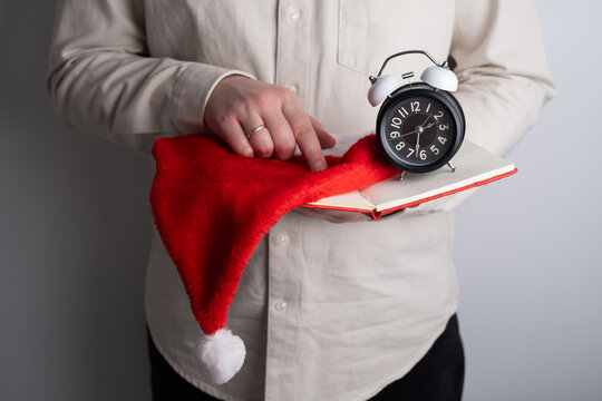 Man planning holiday schedule with alarm clock and santa hat