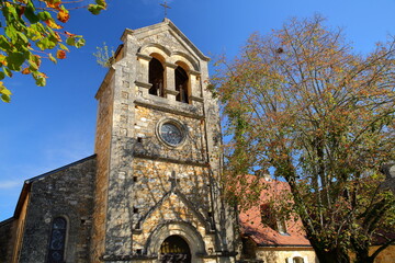 The bell tower of the christian and medieval church Saint Michel Archange in Castelnaud, Dordogne, France, with Autumn colors