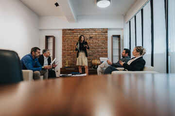 A business team collaborating in a contemporary office. A female presenter leads the discussion.