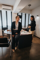 Two businesswomen interact in a contemporary office setting, engaging in a professional discussion. The scene highlights teamwork, productivity, and a formal workplace atmosphere.