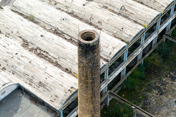 Aerial view of a towering brick chimney piercing through the decaying concrete roof of an abandoned industrial complex, Sarajevo, Federation of Bosnia and Herzegovina, Bosnia and Herzegovina.