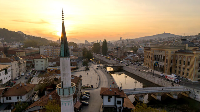 Aerial view of the Gazi Husrev-beg Mosque's minaret piercing the golden sunrise, casting shadows on the Miljacka River, Sarajevo, Federation of Bosnia and Herzegovina, Bosnia and Herzegovina.