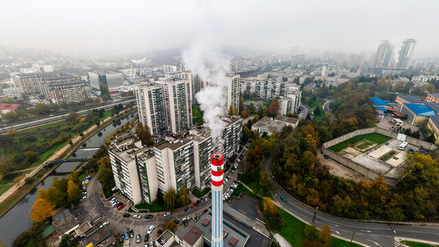 Aerial view of a towering chimney releasing plumes of smoke amidst residential buildings and autumn foliage, Sarajevo, Federation of Bosnia and Herzegovina, Bosnia and Herzegovina.