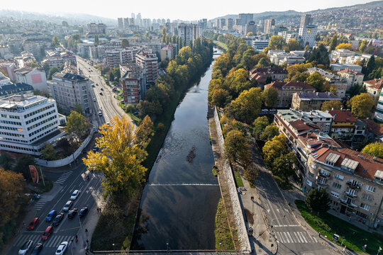 Aerial view of the Miljacka River flowing through Sarajevo's urban landscape, framed by autumn foliage and modern buildings, Sarajevo, Federation of Bosnia and Herzegovina, Bosnia and Herzegovina.