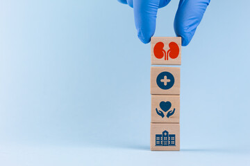 A doctor wearing a blue glove sorts and organizes wooden cubes with a kidney icon and medical...