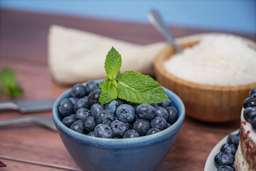 A generous pile of blueberries rests on an aged pine board, showcasing the natural variations in...