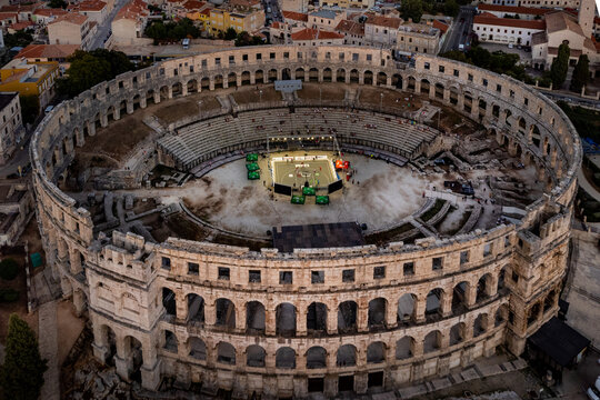 Pula, Croatia - 17 November 2025: Aerial view of the magnificent Pula Arena bathed in the soft glow of twilight, its ancient stones standing in stark contrast to the modern stage within.