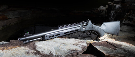 Small waterfall in the dark behing a black lever action rifle