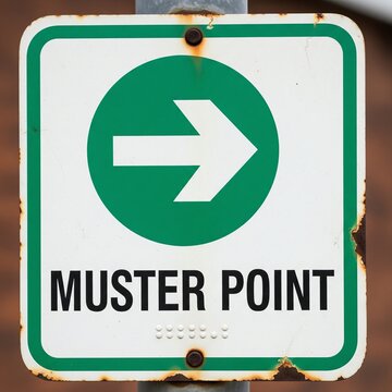 Square sign with green border and arrow indicating Muster Point Keywords: sign, muster point