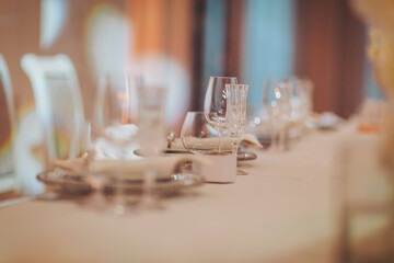 Elegant table setting for a formal dinner event, featuring glassware and fine dinnerware arranged meticulously for guests in a softly lit venue