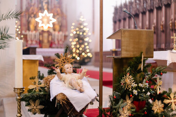 Infant Jesus in the Manger with Bethlehem Star and Christmas Decorations Inside a European Church. Catholic holiday culture. Sacred faith.