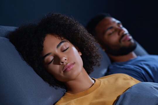 A couple enjoys a restful sleep in a cozy, dark environment