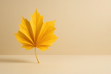 Golden maple leaf folded like a fan on beige background with soft lighting and empty space for text elegant autumn concept for seasonal business fashion and lifestyle marketing visuals