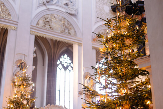 Christmas Tree and Advent Decorations Inside a European Church with Straw Ornaments, Candles, and Warm Holiday Light