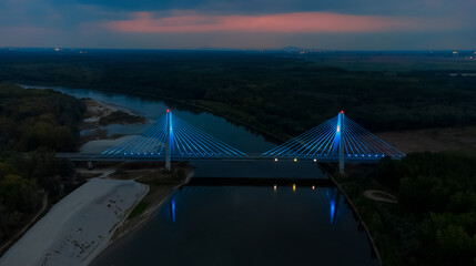 Aerial view of a striking bridge adorned with blue lights spans the dark river against a backdrop of twilight, Osijek, Osijek-Baranja County, Croatia.