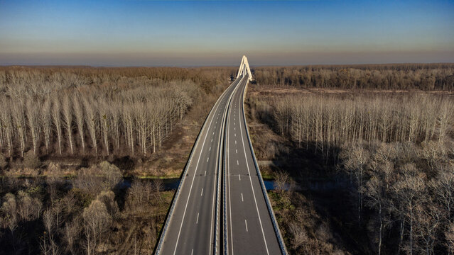 Aerial view of the modern cable-stayed bridge stretches across the landscape, a stark white contrast against the muted tones of the winter trees, Osijek, Osijek-Baranja County, Croatia.