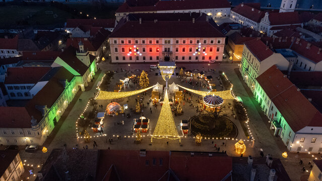 Aerial view of a festive square adorned with twinkling lights and Christmas trees, framed by historic buildings with red and white lights, Osijek, Osijek-Baranja County, Croatia.