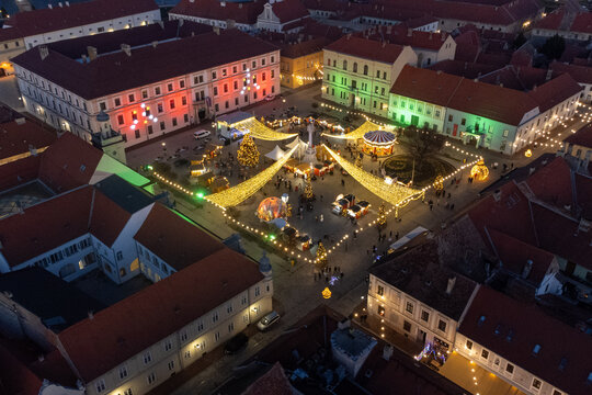 Aerial view of festive lights illuminate the main square, showcasing the vibrant Christmas market with the Holy Trinity Column as a focal point, Osijek, Osijek-Baranja County, Croatia.
