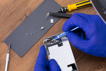 The master's hands use tools to disassemble the phone display
