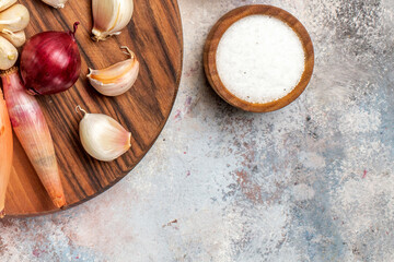 Cooking ingredients with red onion, garlic cloves, and coarse salt in a wooden bowl