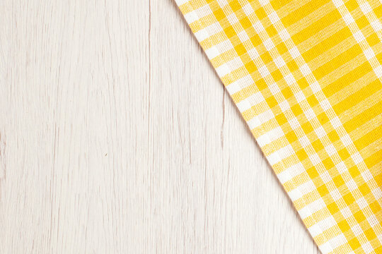White washed wood texture background with a vibrant yellow gingham tablecloth corner