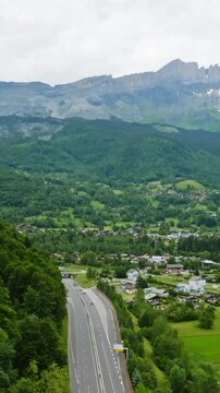 Vertical drone shot tilting over traffic on road N205 toward mountains of France