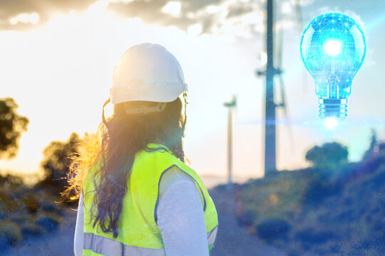 Female engineer analyzing wind turbines: planning sustainable energy solutions at sunset