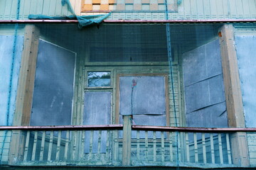 Façade de maison abandonnée derrière une bâche transparente.