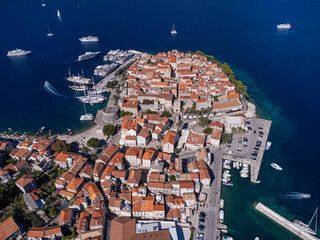 Aerial view of the historic old town with its red-tiled roofs contrasting against the deep blue sea, framed by boats and yachts, Korcula, Dubrovnik-Neretva County, Croatia.