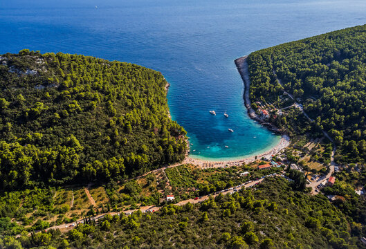 Aerial view of inviting turquoise waters meet the shore, embraced by verdant hills, boats bob gently in the bay, Korcula, Dubrovnik-Neretva County, Croatia.