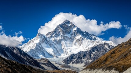 Snowy mountain peak rises majestically under a blue sky partially covered with white clouds during daytime.