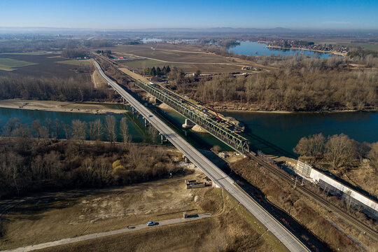 Aerial view of the contrasting blue water flowing under the parallel bridges, connecting vibrant green forests and dry fields, Koprivnica, Koprivnica-Krizevci County, Croatia.