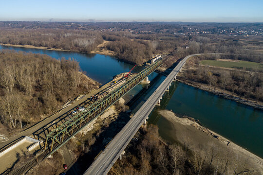 Aerial view of parallel bridges, one a green truss railway bridge and the other a concrete road bridge, stretching over a wide river, Koprivnica, Koprivnica-Krizevci County, Croatia.