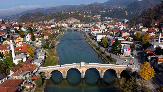 Aerial view of a stone bridge gracefully arches over the Neretva River, reflecting the autumn sunlight amidst the townscape, Konjic, Federation of Bosnia and Herzegovina, Bosnia and Herzegovina.