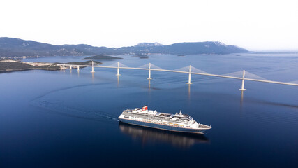 Komarna, Croatia - 14 November 2025: Aerial view of the majestic cruise ship sailing under the soaring Peljesac Bridge, amidst the serene Adriatic Sea.