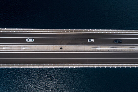 Aerial view of cars glide smoothly across a modern bridge, contrasting with the deep blue sea below, Komarna, Dubrovnik-Neretva County, Croatia.