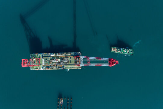 Aerial view of the Peljesac Bridge section being transported, its red and white support contrasting with the deep blue sea, Komarna, Dubrovnik-Neretva County, Croatia.
