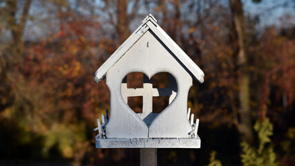 Wooden bird feeder with berries and wheat inside, birdhouse on a beautiful blurred background of yellow leaves outdoors. feeders in the autumn park. feed wild birds during the cold season. close-up