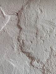Obraz premium A close up view of a rough plaster wall texture showing natural bumps, cracks, and uneven surface patterns. Suitable for use as a background, material reference, or design texture