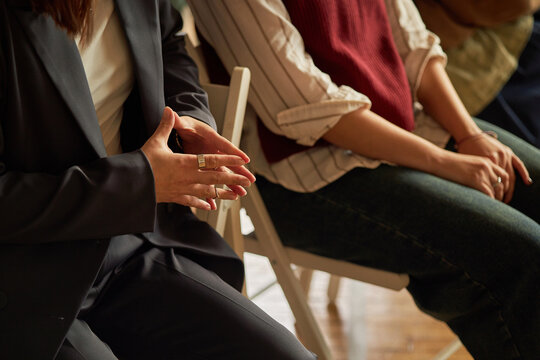 Woman gesturing with hands while sitting next to teenagers during psychology class, focusing on discussion in educational setting