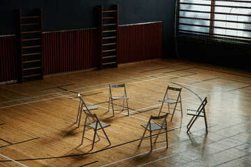 Empty chairs arranged in circle standing on floor suggesting group therapy or psychology class setting for students with copy space in background