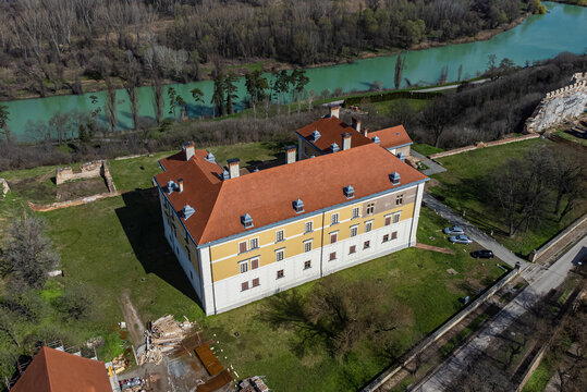 Aerial view of the Odescalchi Castle with its vibrant orange roof contrasting against the muted green river and surrounding trees, Ilok, Vukovar-Srijem County, Croatia.